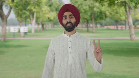 Sikh-Indian-man-showing-victory-sign-in-park