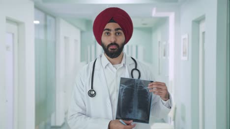 Médico-Indio-Sikh-Serio-Explicando-El-Informe-De-Rayos-X-Al-Paciente
