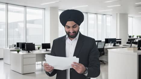 Glücklicher-Indischer-Sikh-Geschäftsmann,-Der-Unternehmensberichte-Liest