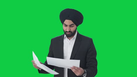 Serious-Sikh-Indian-businessman-reading-company-reports-Green-screen