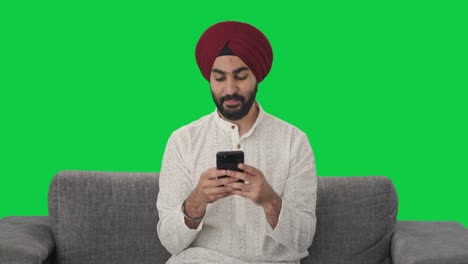 Glücklicher-Sikh-Indianer,-Der-Jemandem-Eine-Nachricht-Auf-Grünem-Bildschirm-Sendet