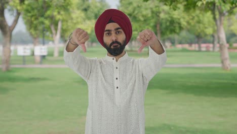 Disappointed-Sikh-Indian-man-showing-thumbs-down-in-park