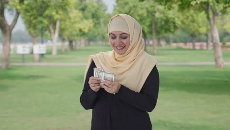 Glückliche-Muslimische-Frau,-Die-Im-Park-Geld-Zählt