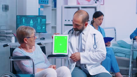 Practitioner-holding-mock-up-tablet-in-recovery-center-for-elderly-disabled-patients