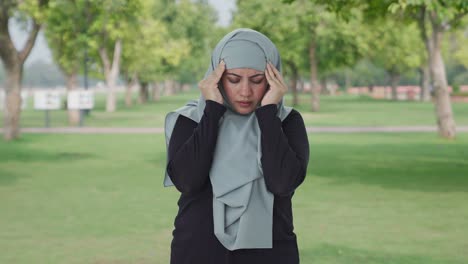 Kranke-Muslimische-Frau,-Die-Im-Park-Unter-Kopfschmerzen-Leidet