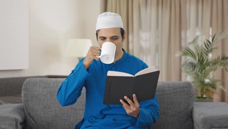 Hombre-Musulmán-Feliz-Leyendo-Un-Libro-Y-Bebiendo-Té