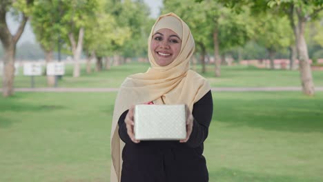 Glückliche-Muslimische-Frau,-Die-Im-Park-Ein-Geschenk-Macht