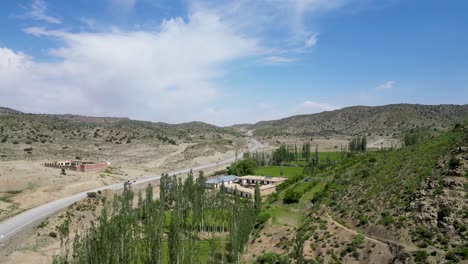 Drone-sees-Paktia's-green-mountains-in-Afghanistan,-divided-by-a-road