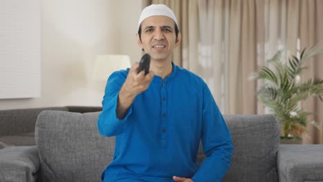Frustrated-Muslim-man-trying-to-fix-television-remote