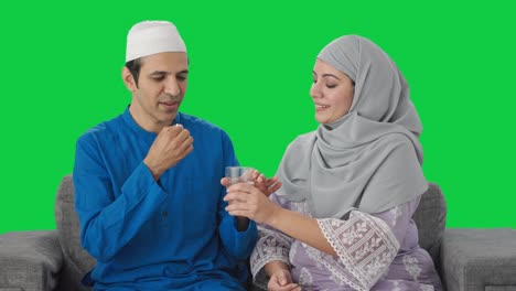 Feliz-Esposa-Musulmana-Dándole-Medicina-A-Su-Marido-Pantalla-Verde