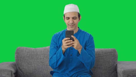 Glücklicher-Muslimischer-Mann,-Der-Auf-Dem-Grünen-Bildschirm-Des-Telefons-SMS-Schreibt