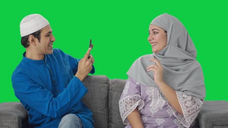 Glücklicher-Muslimischer-Ehemann,-Der-Auf-Bilder-Seiner-Frau-Auf-Grünem-Bildschirm-Klickt