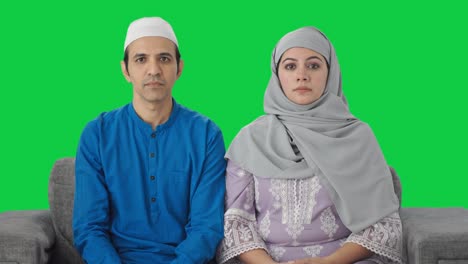 Ernsthaftes-Muslimisches-Paar,-Das-Auf-Den-Grünen-Bildschirm-Der-Kamera-Starrt