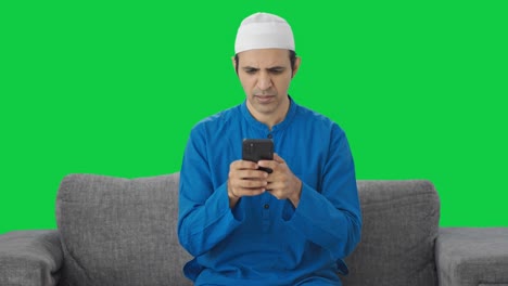 Wütender-Muslimischer-Mann,-Der-Auf-Dem-Grünen-Bildschirm-Des-Telefons-SMS-Schreibt