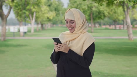 Happy-Muslim-woman-chatting-on-phone-in-park