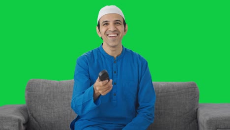 Glücklicher-Muslimischer-Mann,-Der-Lacht,-Während-Er-Den-Grünen-Bildschirm-Im-Fernsehen-Sieht