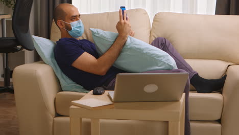 Man-with-disposable-mask-on-sofa