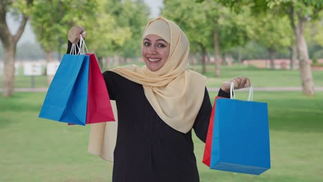 Glückliche-Muslimische-Frau-Posiert-Mit-Einkaufstüten-Im-Park