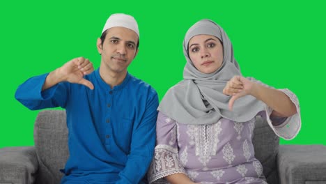 Enttäuschtes-Muslimisches-Paar-Zeigt-Daumen-Nach-Unten-Auf-Grünem-Bildschirm