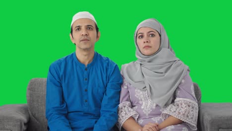 Muslimisches-Paar,-Das-Zu-Hause-Fernsieht,-Grüner-Bildschirm