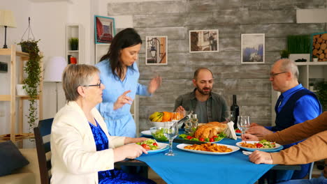 Woman-bringing-roasted-chicken-to-the-table-at-family-dinner