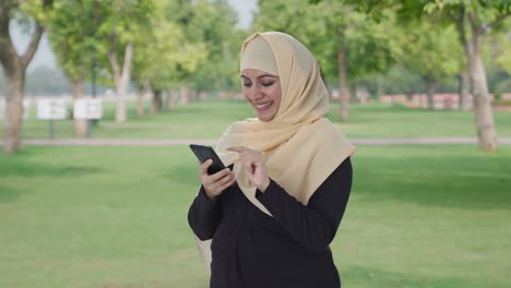 Mujer-Musulmana-Feliz-Usando-El-Teléfono-En-El-Parque