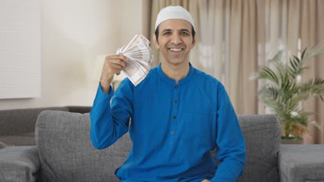 Happy-Muslim-man-using-money-as-fan