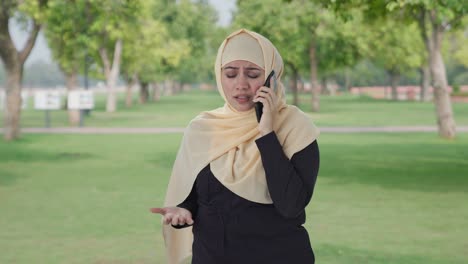 Mujer-Musulmana-Enojada-Hablando-Por-Teléfono-En-El-Parque