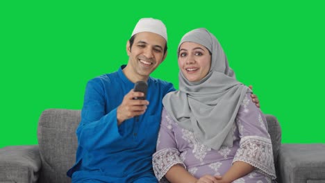 Happy-Muslim-couple-watching-TV-Green-screen