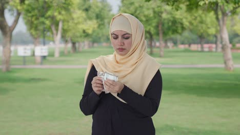 Traurige-Muslimische-Frau,-Die-Im-Park-Geld-Zählt