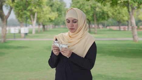 Serious-Muslim-woman-counting-money-in-park