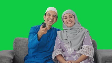 Glückliches-Muslimisches-Paar,-Das-Lacht,-Während-Es-Auf-Dem-Grünen-Bildschirm-Fernsieht