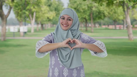 Feliz-Mujer-Musulmana-Mostrando-El-Signo-Del-Corazón-En-El-Parque