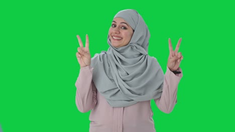 Glückliche-Muslimische-Geschäftsfrau-Zeigt-Siegeszeichen-Auf-Grünem-Bildschirm