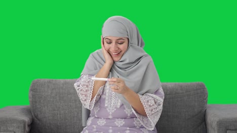 Glückliche-Muslimische-Frau,-Die-Den-Schwangerschaftstest-Auf-Grünem-Bildschirm-überprüft