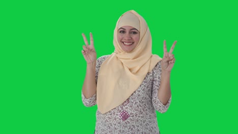 Fröhlicher-Muslimischer-Lehrer-Zeigt-Siegeszeichen-Auf-Grünem-Bildschirm