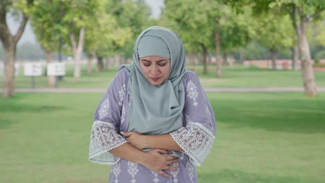 Mujer-Musulmana-Que-Sufre-De-Dolor-De-Estómago-En-El-Parque