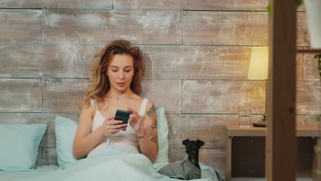 Zoom-in-shot-of-beautiful-woman-in-pajamas-using-smartphone