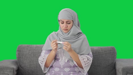 Traurige-Muslimische-Frau-überprüft-Den-Grünen-Bildschirm-Des-Schwangerschaftstests