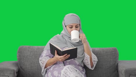 Glückliche-Muslimische-Frau,-Die-Ein-Buch-Liest-Und-Tee-Trinkt,-Grüner-Bildschirm