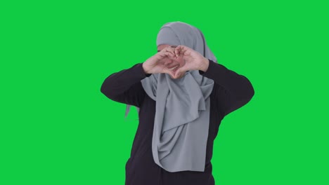 Fröhliche-Muslimische-Frau-Zeigt-Herzzeichen-Auf-Grünem-Bildschirm