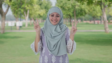Happy-Muslim-woman-showing-victory-sign-in-park
