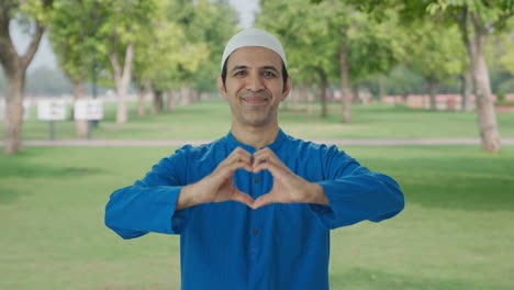 Hombre-Musulmán-Feliz-Sonriendo-Y-Mostrando-El-Signo-Del-Corazón-En-El-Parque