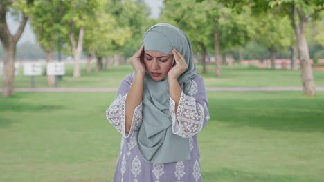 Kranke-Muslimische-Frau,-Die-Im-Park-Unter-Kopfschmerzen-Leidet