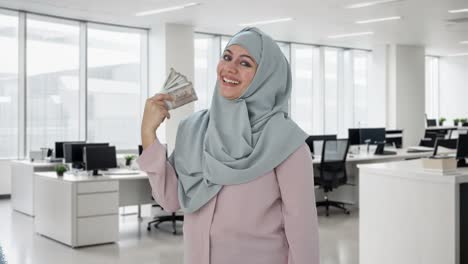 Glückliche-Muslimische-Geschäftsfrau,-Die-Geld-Als-Fan-Verwendet