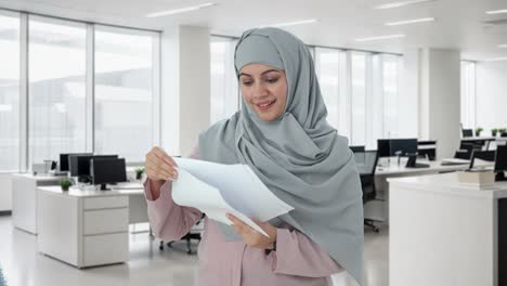 Glückliche-Muslimische-Geschäftsfrau,-Die-Berichte-Liest