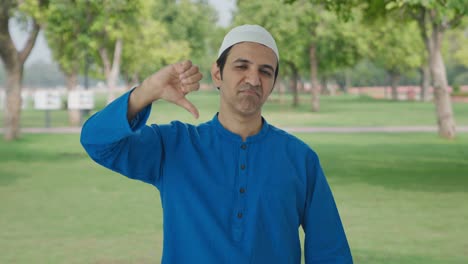 Disappointed-Muslim-man-showing-thumbs-down-in-park