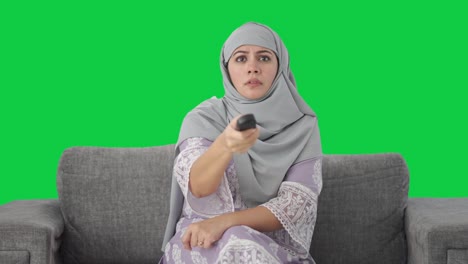 Mujer-Musulmana-Enojada-Tratando-De-Arreglar-La-Pantalla-Verde-Del-Control-Remoto-De-La-Televisión