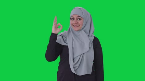 Fröhliche-Muslimische-Frau,-Die-Ein-Okay-Zeichen-Auf-Grünem-Bildschirm-Zeigt