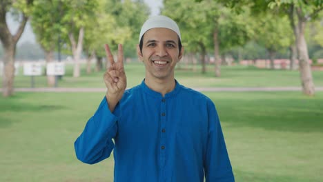 Hombre-Musulmán-Feliz-Mostrando-El-Signo-De-La-Victoria-En-El-Parque